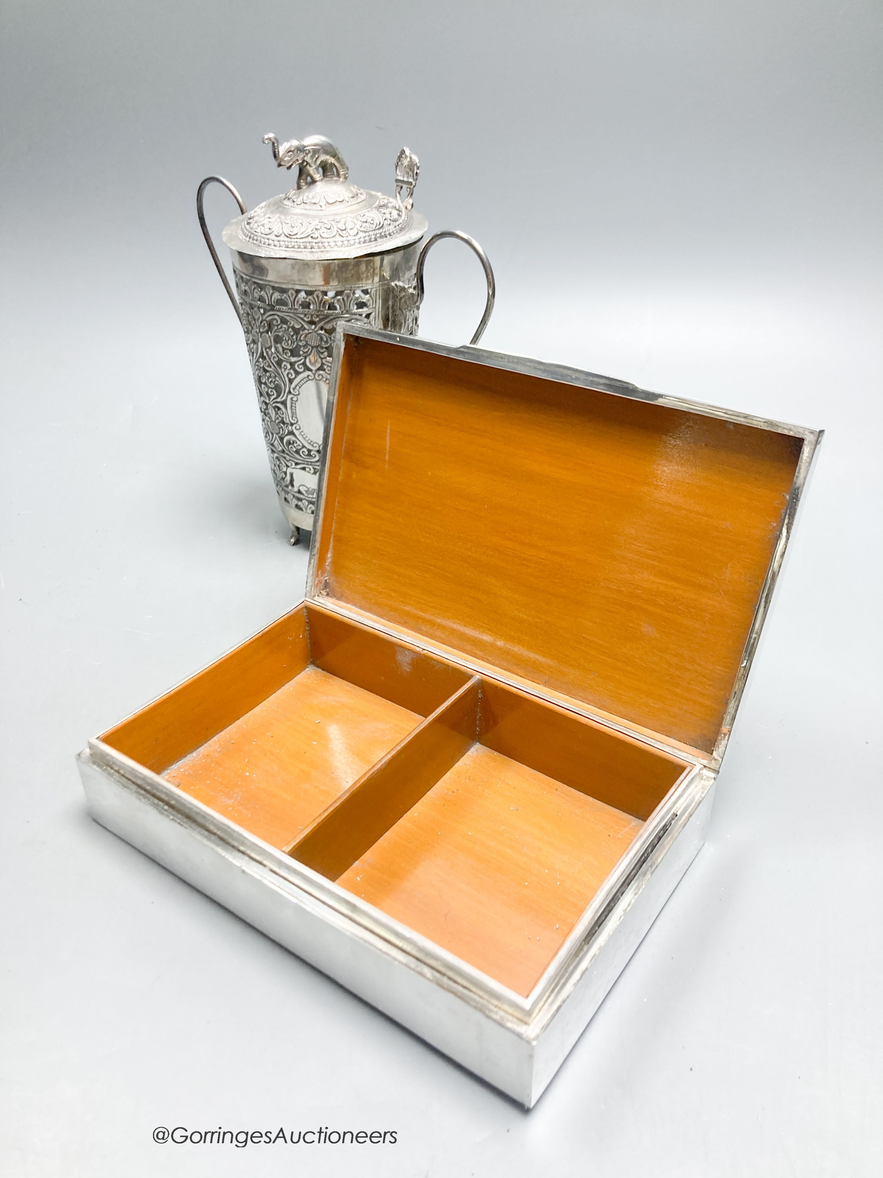A Thai white metal rectangular cigarette box with embossed lid, 17cm and a Thai white metal cocktail mixer, cover and spoon, engraved